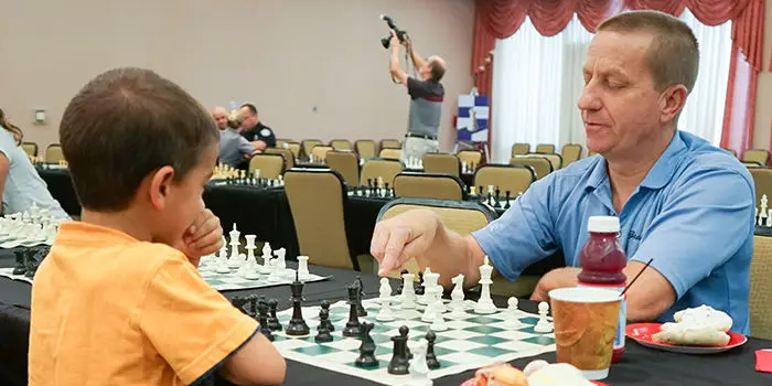 A man and a kid playing chess at the Open Play Chess event of the Sunrise Center for Excellence in Chess